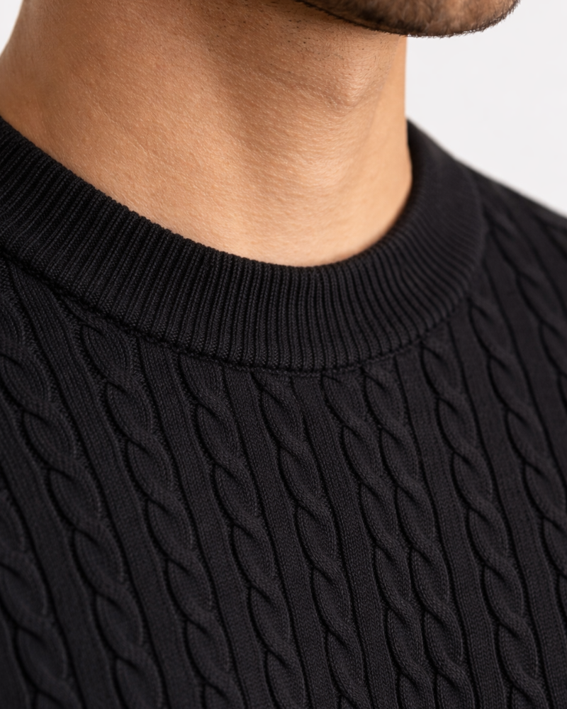 Close-up of black cotton cable knit texture. Minimalist luxury ribbed crewneck with intricate premium weave.