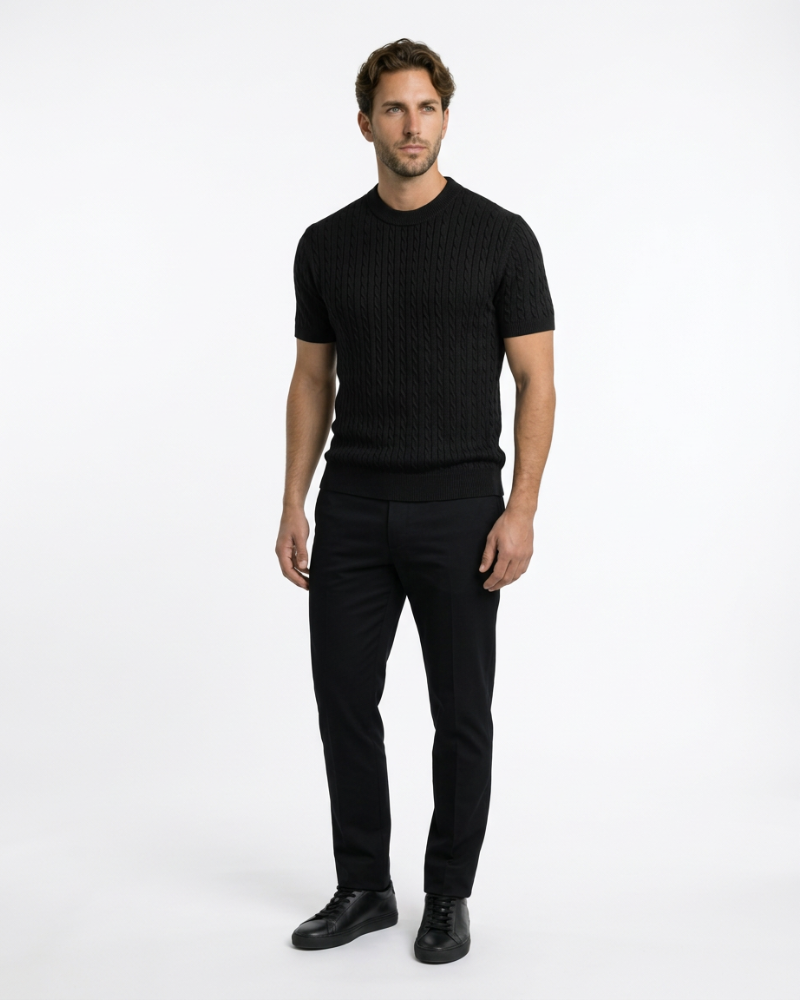 A man in a black cotton cable knit t-shirt and trousers. Minimalist luxury aesthetic with a slim-fit knit texture.