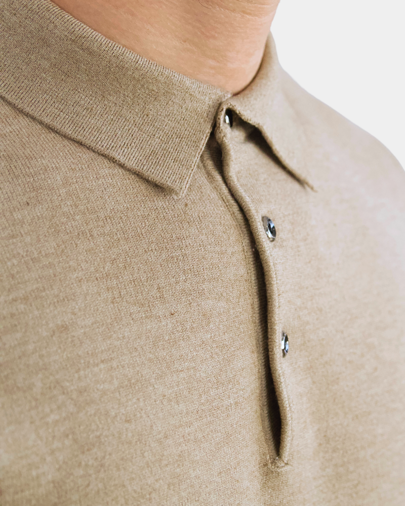 Close-up of luxury beige cashmere-wool knit. Minimalist heathered texture with refined collar and button details.