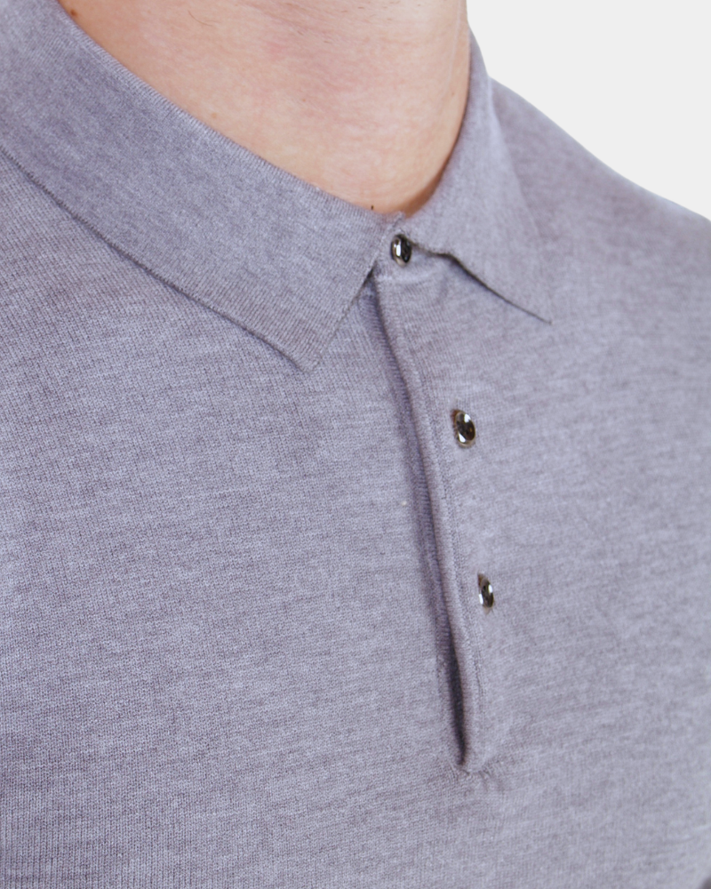 Close-up of luxury grey merino wool knit. Minimalist heathered texture with a sharp collar and polished button detail.