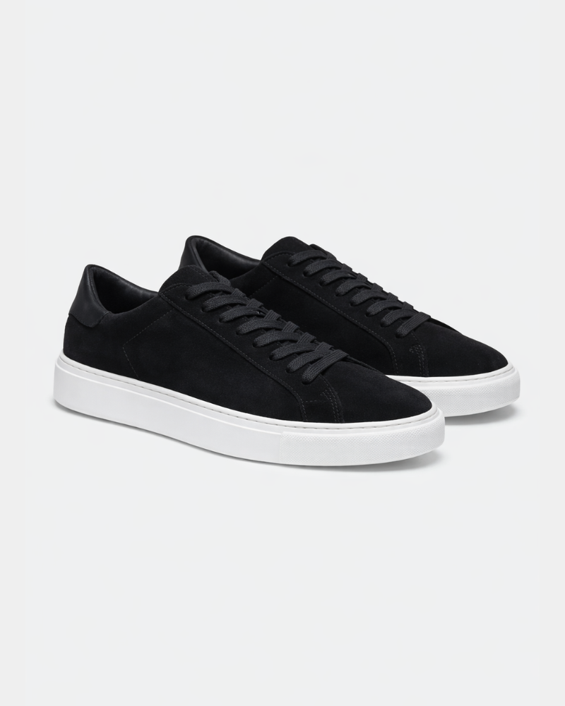 Minimalist luxury black suede trainers featuring tonal laces and premium white soles in a sophisticated angled view. #color_black