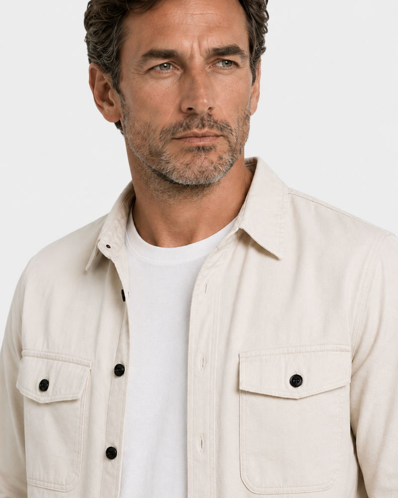 Close-up of a person wearing a By Alden beige button-up shirt over a white t-shirt. #color_deep stone