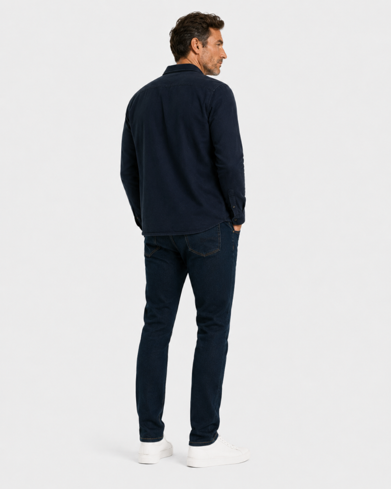 Man wearing a By Alden navy long-sleeve shirt and dark jeans on a white background #color_navy