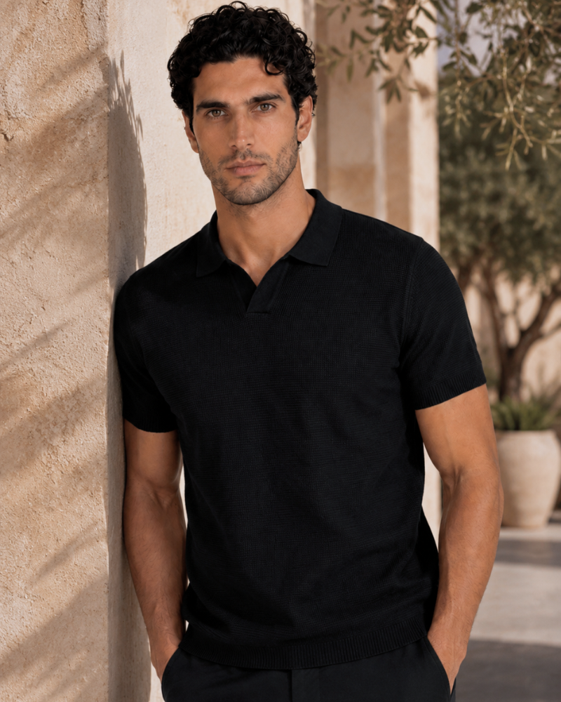 By Alden black open-collar knit polo shirt on male model, front view, upper body, outdoor warm beige wall background. #color_black