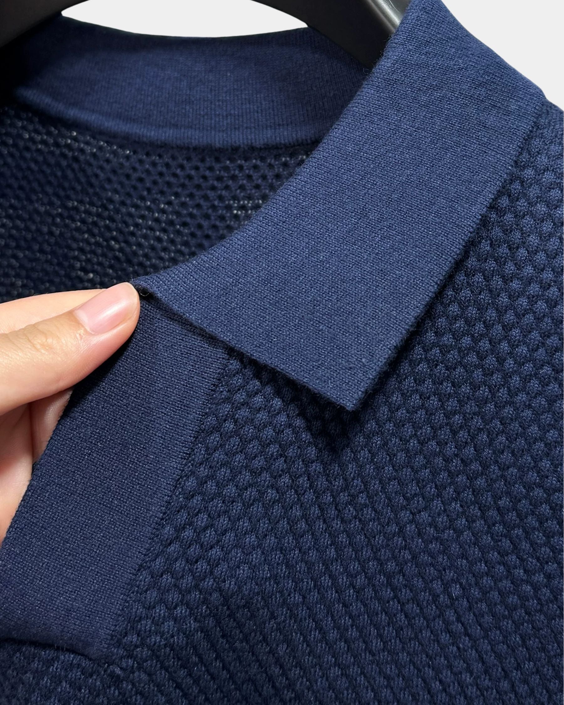 By Alden navy blue open-collar knit polo shirt collar and fabric texture detail, hand holding collar, close-up, navy background. #Color_navy
