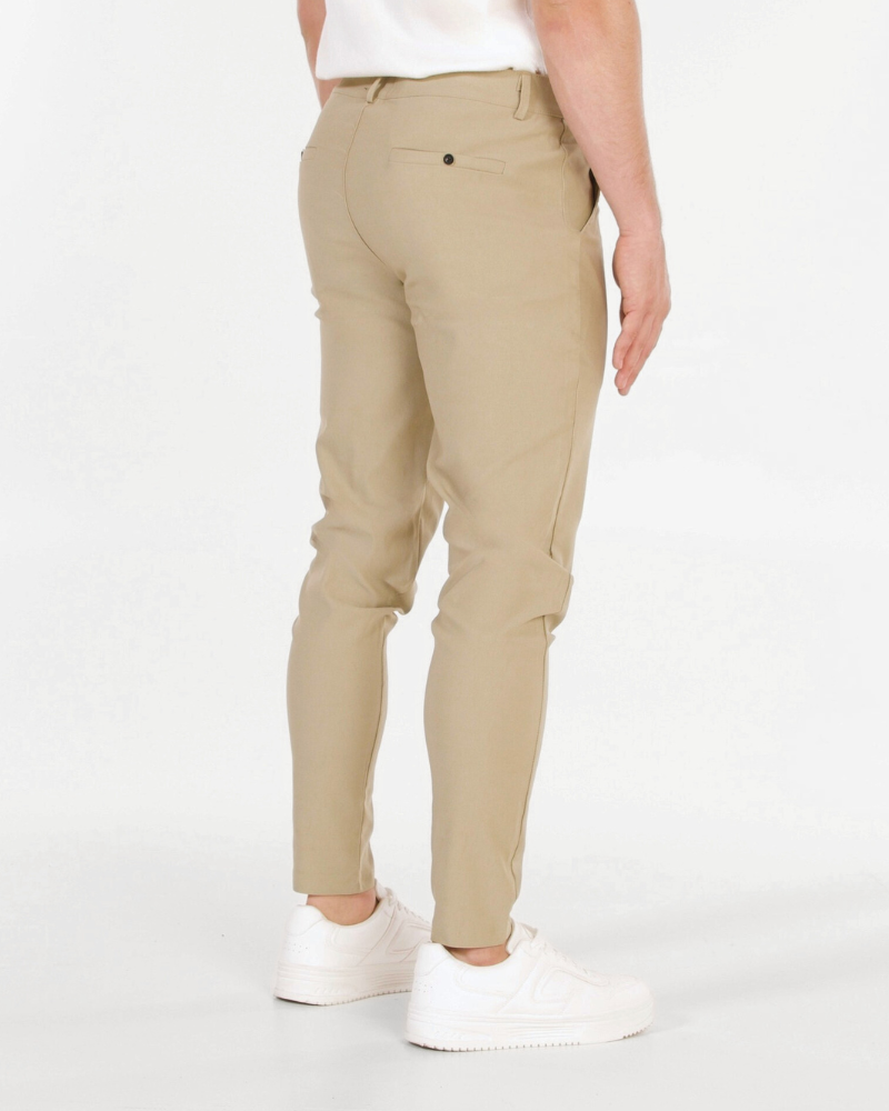 Minimalist luxury beige stretch cotton chinos in a slim fit, featuring a smooth matte texture and welt back pockets.