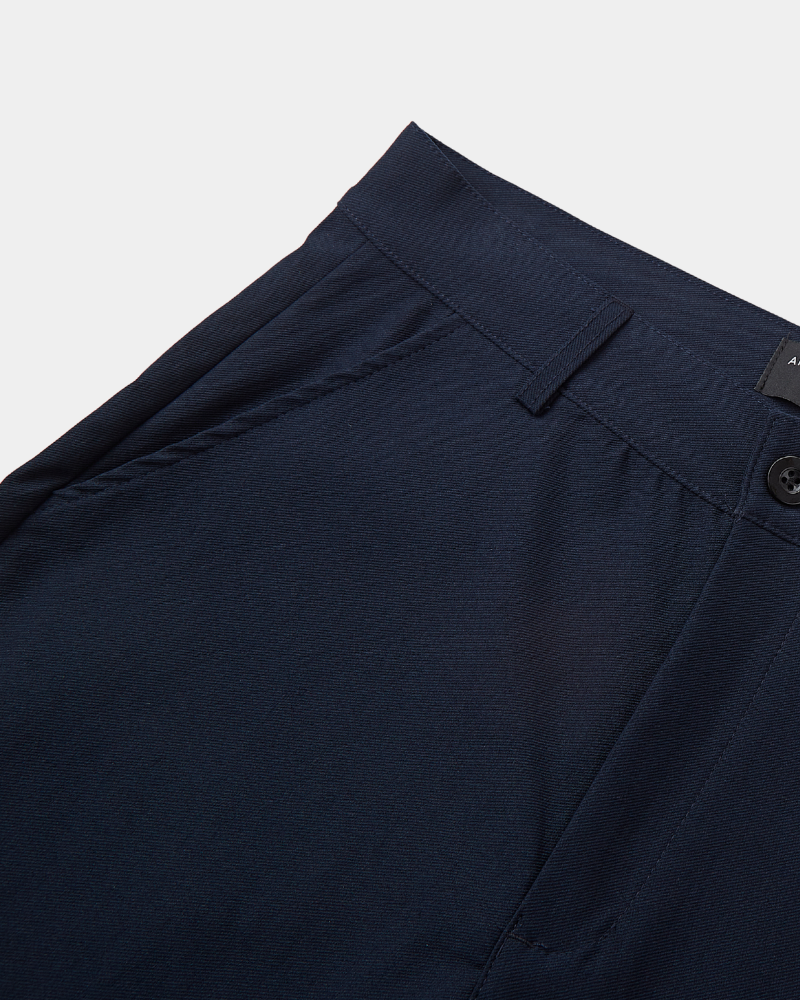 Close-up of minimalist luxury navy chinos in a breathable twill cotton-stretch fabric with a clean-tailored waistband.