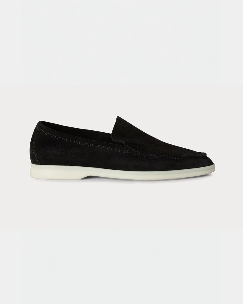 Minimalist luxury black suede loafers with contrast white rubber soles, featuring a sleek, almond-toe slip-on fit.