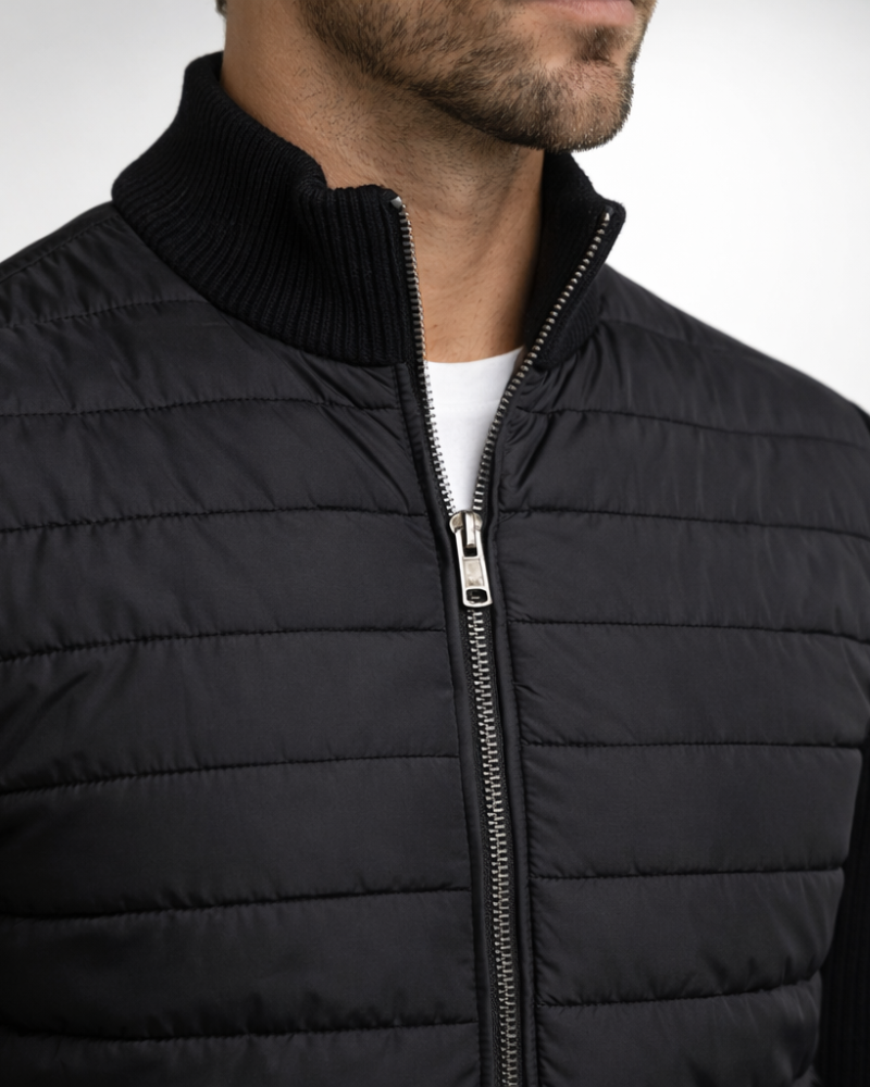 By Alden Black Hybrid Puffer Knit Jacket worn by a White male model, close-up front view of zip and collar detail, light grey background #Color_Black