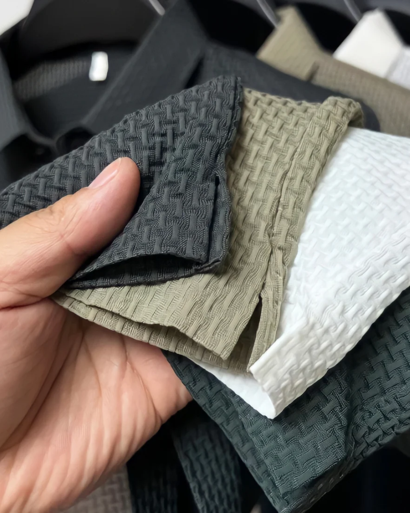 Hand holding fabric By Alden swatches in black, green, and white.