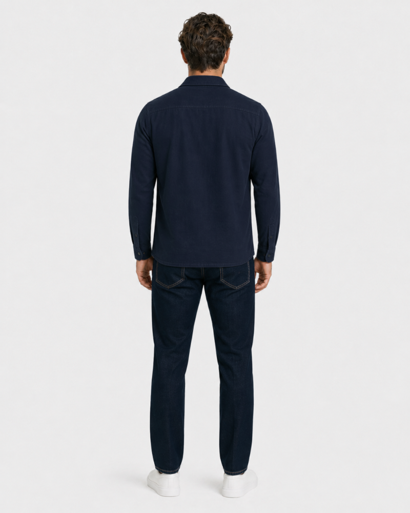 Man wearing a By Alden navy long-sleeve shirt and dark jeans on a white background #color_navy
