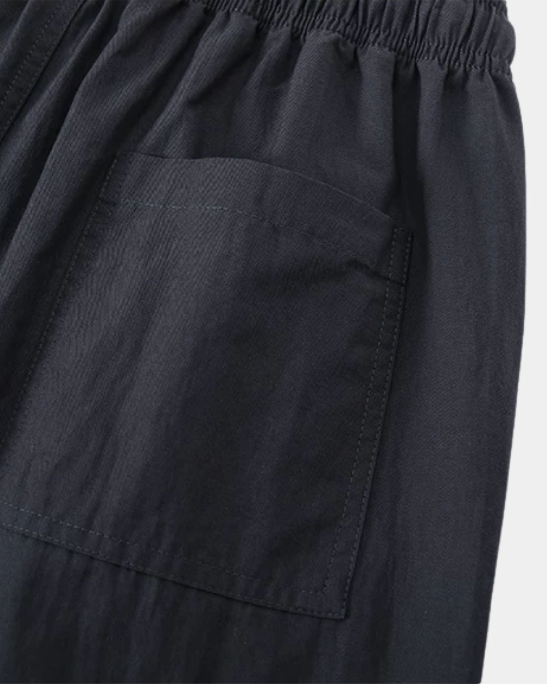 By Alden navy linen drawstring trousers, close-up detail of back pocket and fabric texture, light gray background #color_navy
