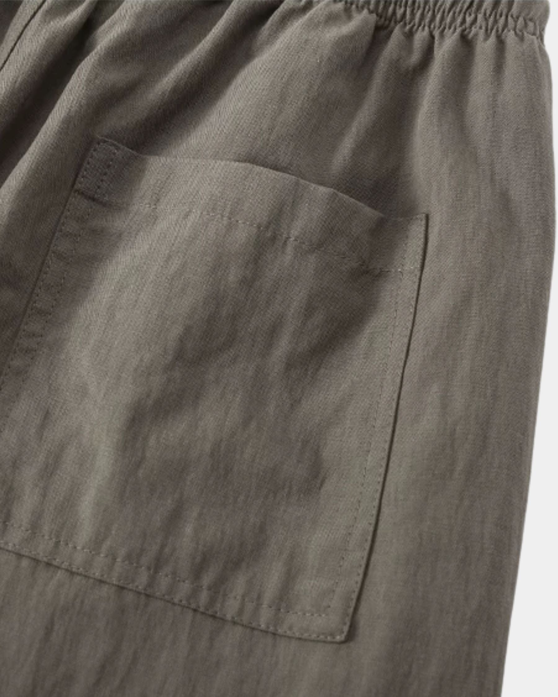 By Alden olive green linen drawstring trousers, close-up detail of back pocket and fabric texture, light gray background #color_olive green