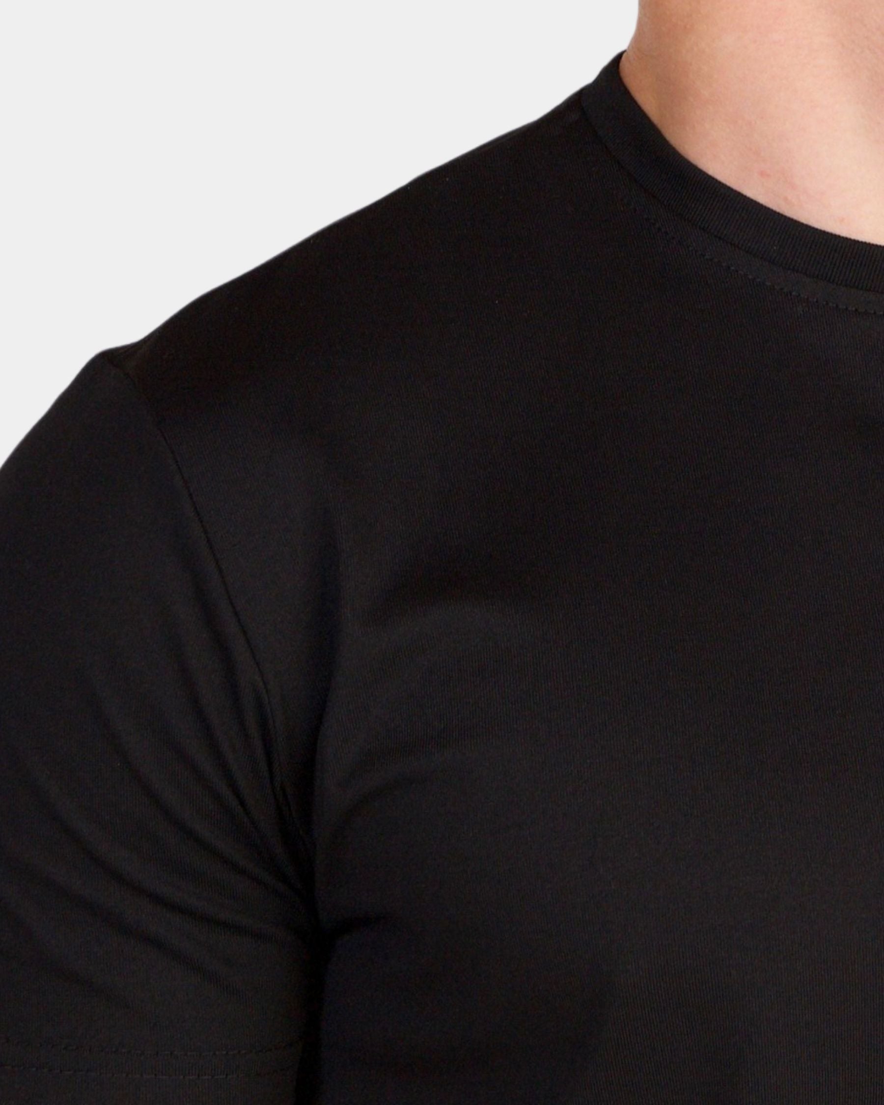 Close-up of a person wearing a plain black short-sleeve crew-neck t-shirt against a light gray background.