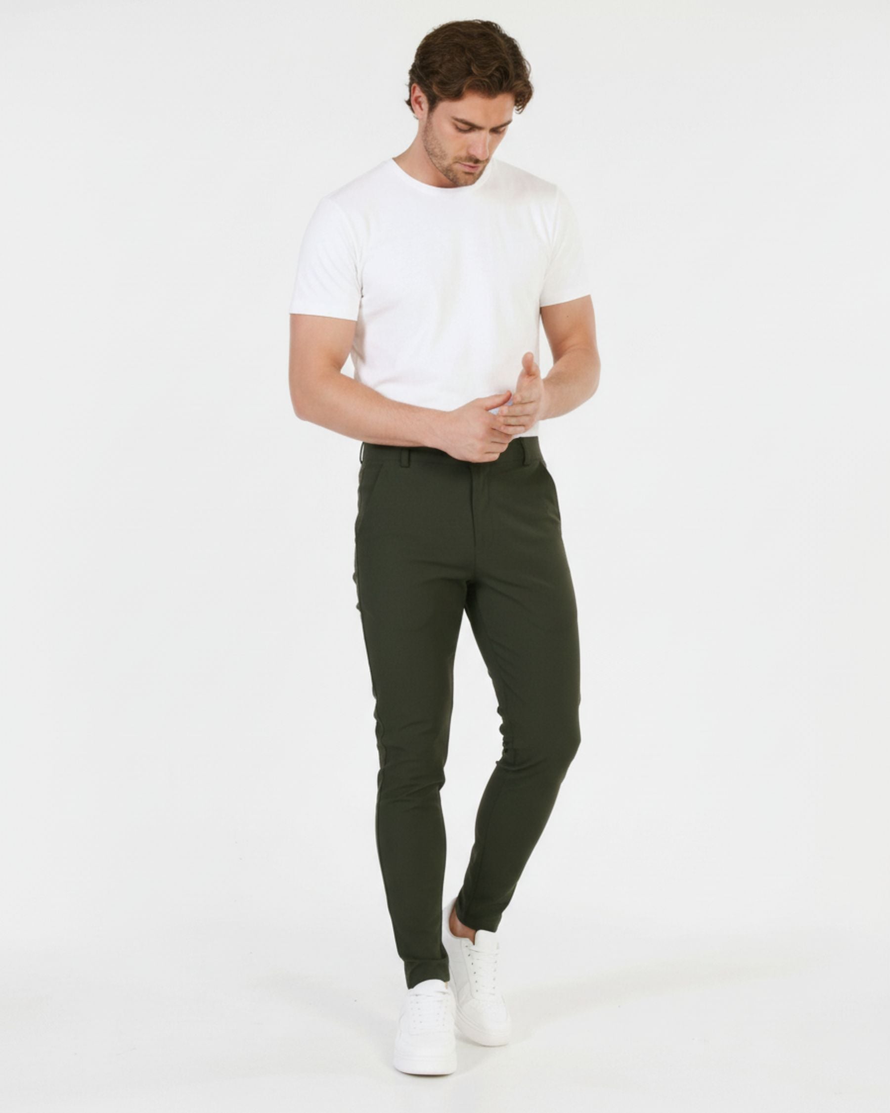 Man wearing a white t-shirt and dark green pants on a white background