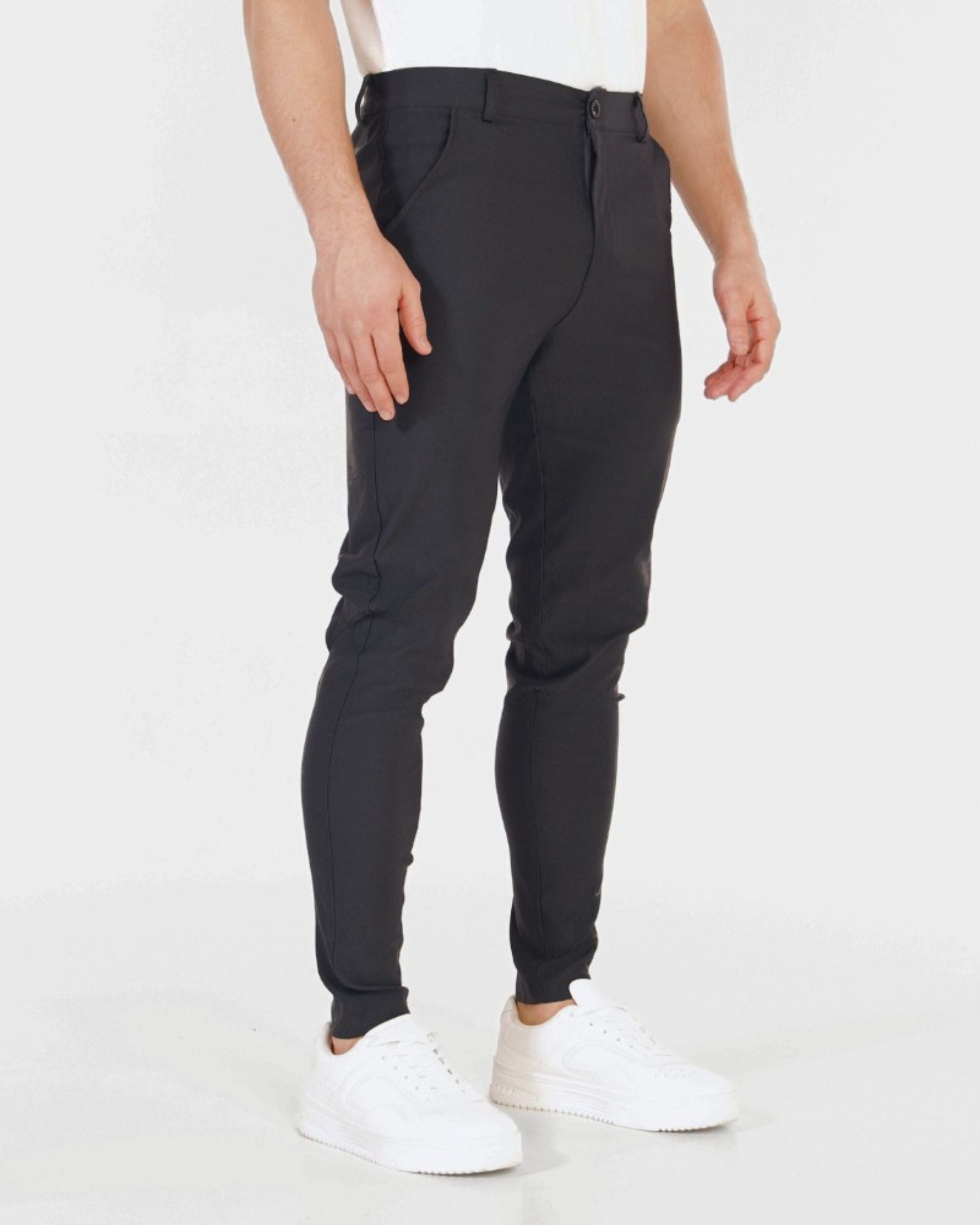 Person wearing black pants and white shoes on a white background