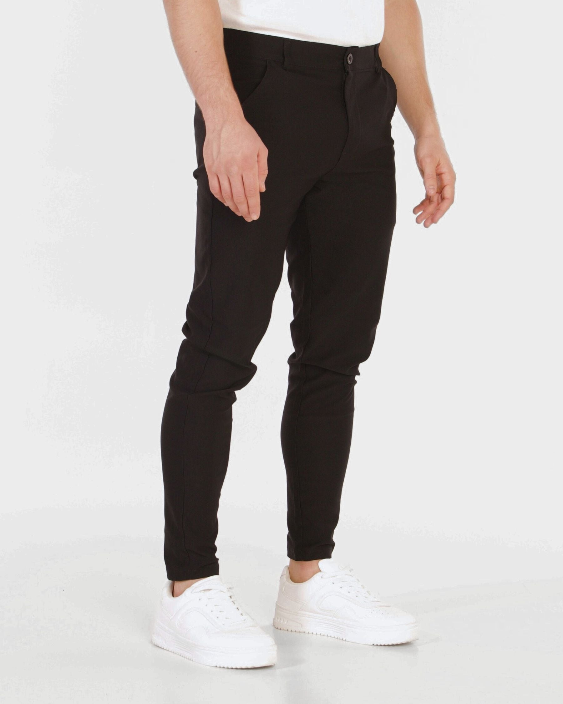 Person wearing black pants and white sneakers on a white background