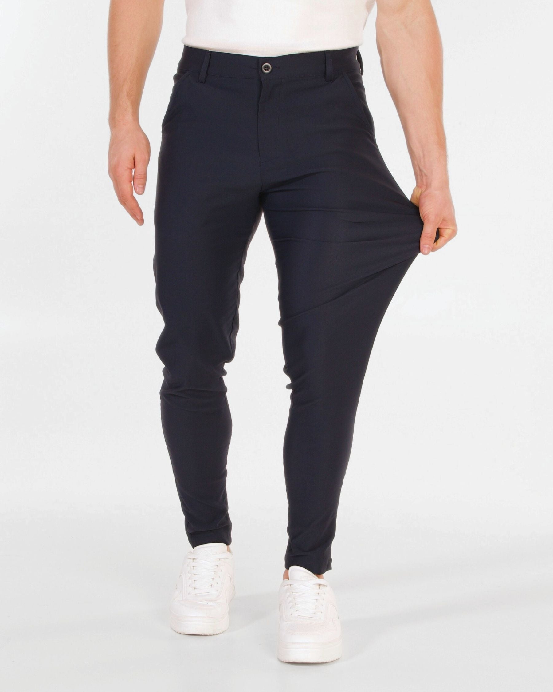 Person wearing navy pants and white shoes on a white background